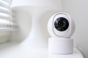 Smart home security camera on a white table near a window. photo