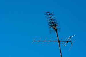 Metal television antenna against clear blue sky photo