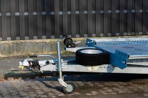 Car trailer on display with single tire resting beside it photo