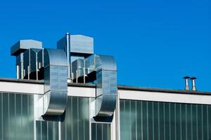 Modern building architecture with metal ventilation pipes in blue sky photo