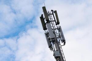 Cell tower stands tall against a cloudy sky in urban setting photo