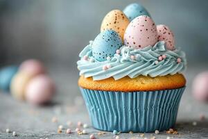 Vanilla cupcake with cream and sweet quail egg decoration stands on a table with a blurred blue background. photo