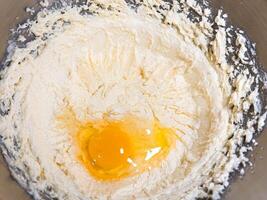 Beating butter, sugar and eggs in a grey metal bowl. The process of making cake and cookies by mixing butter, eggs and sugar. photo