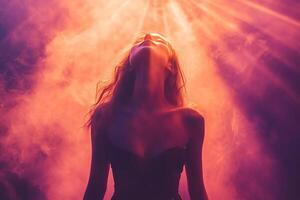 Silhouette of young attractive woman feeling joy in clouds of light smoke under neon lighting. photo