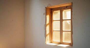 Sunlight streams across a wall illuminating the window and frame. photo