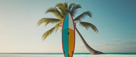 A colorful surfboard is sitting on the beach next to a palm tree photo