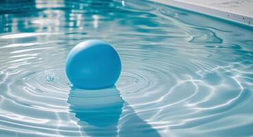 Blue inflatable ball floating on the surface of a clear swimming pool with ripples and reflections Copy Space. photo