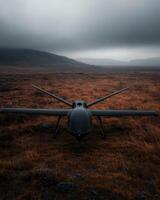 A black drone sits in a grassy field under a cloudy sky photo