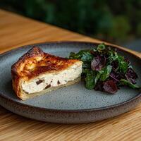 A slice of quiche with a side salad on a plate photo