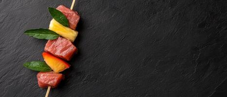 A skewer of meat and fruit on a dark background photo