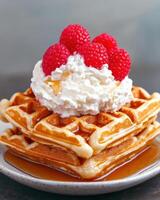 Stack of waffles topped with whipped cream and raspberries photo