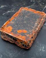 A heavily rusted metal brick on a dark surface photo