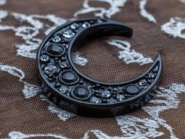 A black crescent moon shaped ornament with embedded gems photo