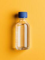 A clear liquid in a glass bottle with a blue cap on a yellow background photo
