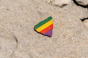 A colorful painted rock on a larger rock photo