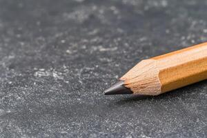 Close up of a sharpened pencil on a textured surface. photo