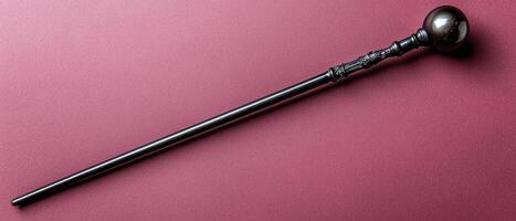 A decorative walking stick with a round handle on a pink background photo
