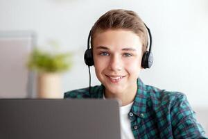 Happy guy in headset using laptop, spending time at home, empty space photo