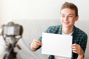 Famous teen blogger showing empty board for advertisement or text while blogging from home, using camera photo