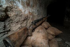 Rifle resting on sandbags in a dark tunnel photo