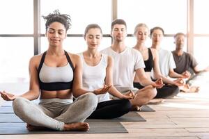 Yoga Class. Group Of Young Sporty People Meditating With Closed Eyes, Sitting In Lotus Position In Studio, Selective Focus At Woman Instructor photo
