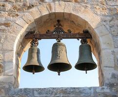 Three ancient bells hanging in stone archway photo