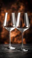 Two empty wine glasses standing on dark table with blurred background photo
