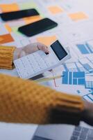 A person is using a calculator on a table with other papers photo