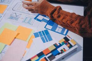 A person is working on a project with a lot of paper and sticky notes photo