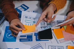 Two people working on a laptop with paper and sticky notes photo