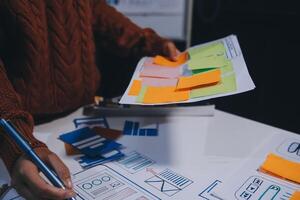 A person is working on a project with paper and sticky notes photo