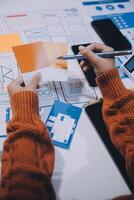 A person is working on a design project with a laptop and paper photo
