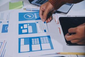 A person is working on a laptop with a tablet and a phone photo