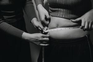 A woman measuring her waist with a tape measure photo