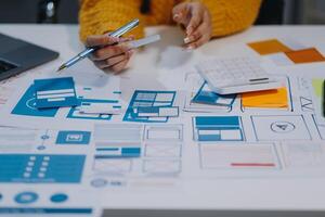 A person is working on a laptop and a paper with various design elements photo