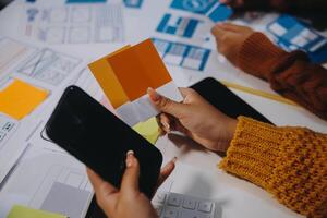 A person holding a smartphone and a piece of paper with a color swatch photo