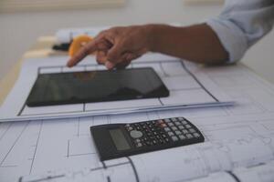 A man using a tablet and calculator to plan a building photo