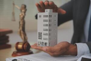 A man in a suit holding a model of a building photo