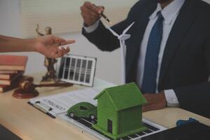 A man in a suit and tie is holding a green house model photo