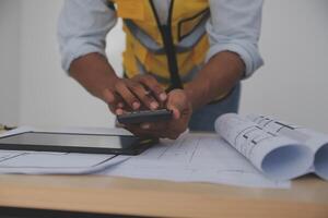 A man in a yellow vest holding a tablet and using a phone photo
