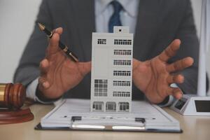A man in a suit is holding a model of a building photo