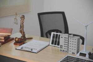 A desk with a statue of a judge, books, and a wind turbine photo