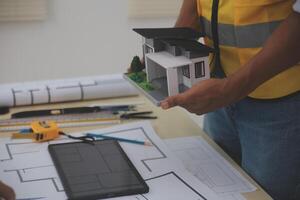 A man holding a model of a house on a table photo