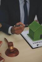 A man signing a contract with a house model photo