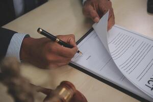 A man signing a contract on a desk photo