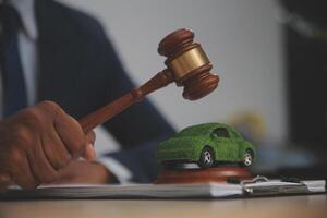 A judge's gavel is used to strike a car model on a desk photo