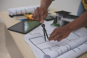 A man is working on a blueprint with a ruler and a compass photo