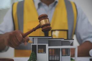 A man holding a gavel over a model of a house photo
