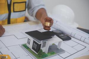 A man holding a gavel and a model of a house photo