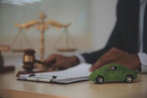 A man in a suit sits at a desk with a green car on the table photo